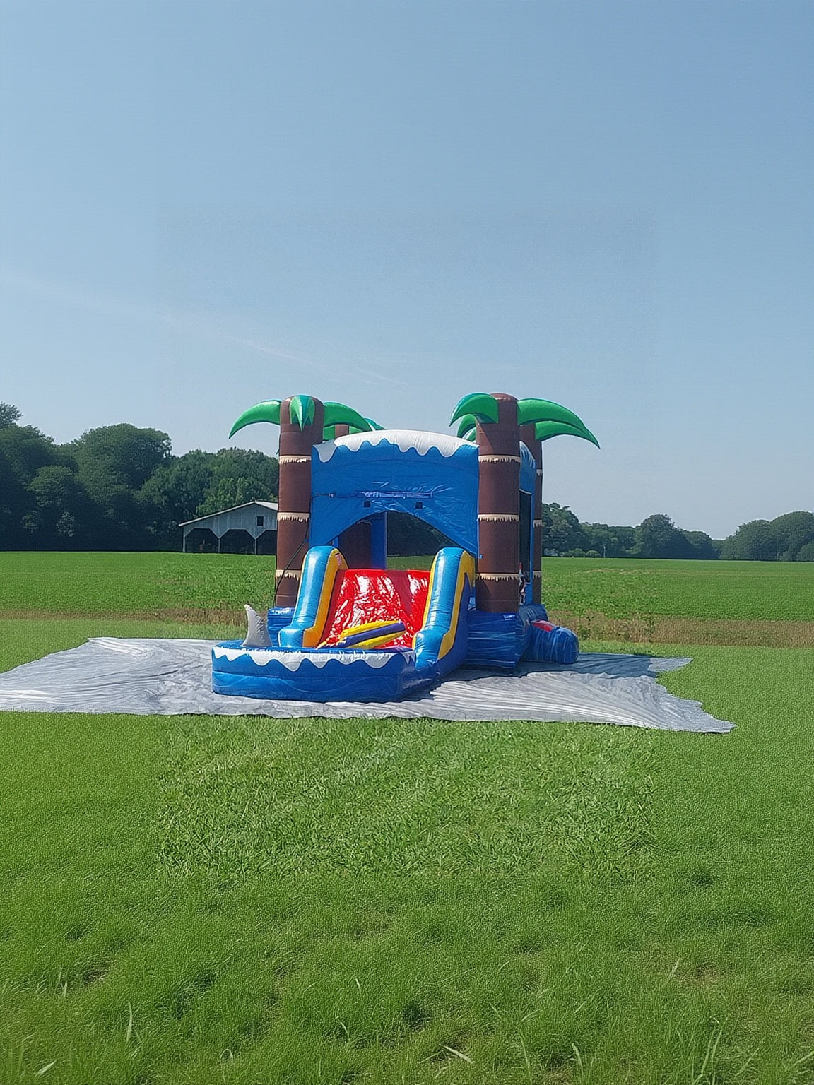 Inflatable water slide with palm trees on a grassy field